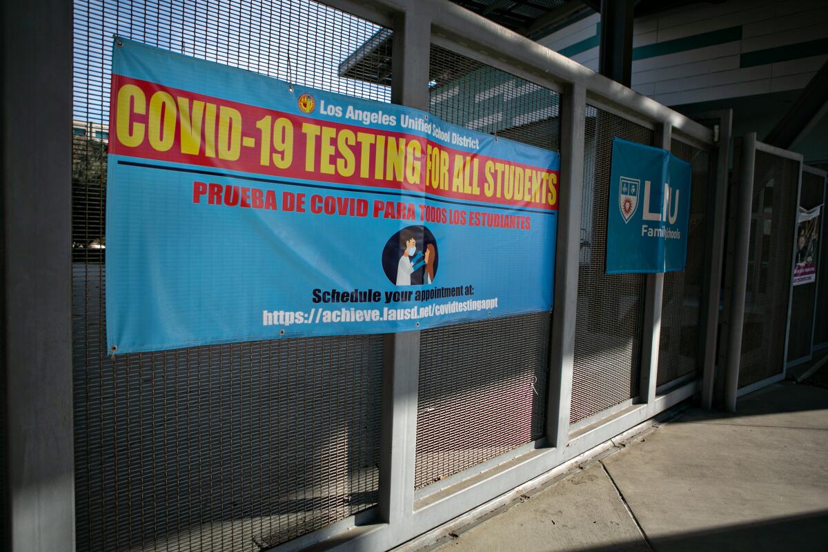 A blue banner offering COVID-19 tests is attached to a fence