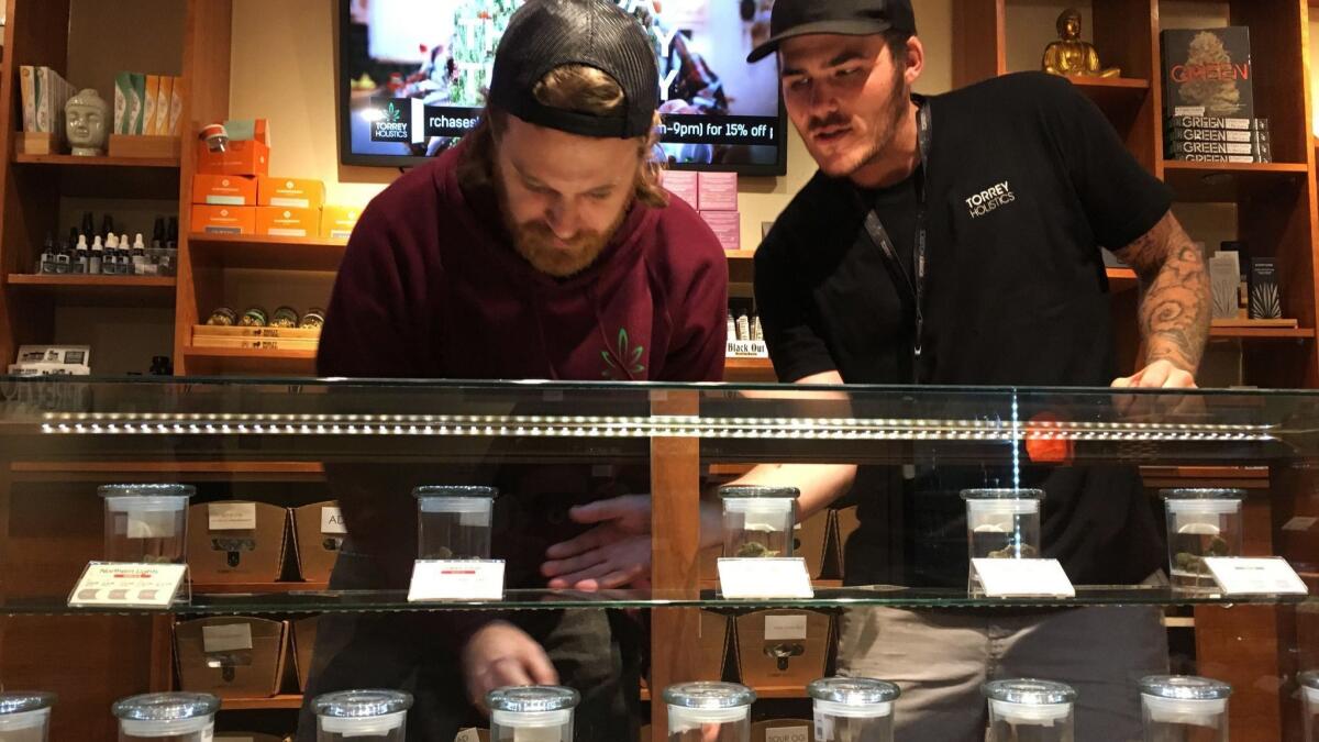 Employees Matt Sullivan, left, and Taron McElroy arrange jars of cannabis at Torrey Holistics in San Diego in 2017.