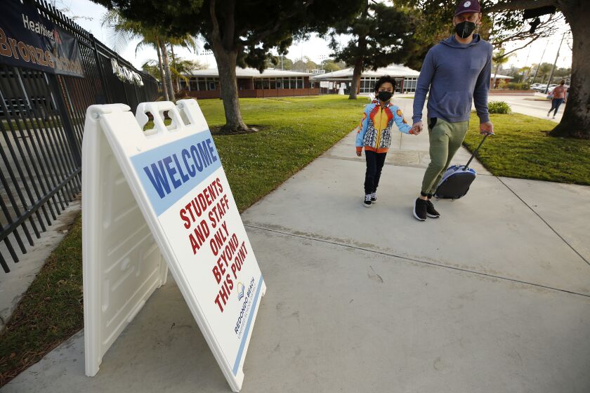 REDONDO BEACH, CA - FEBRUARY 02: Father Alik Laddon helps his first grade student Caden Andino with his backpack as he arrives at Alta Vista Elementary School for the second day of classes as Redondo Beach Unified School district has welcomed back some of its K-2 students this week through a waiver. Alta Vista Elementary School on Tuesday, Feb. 2, 2021 in Redondo Beach, CA. (Al Seib / Los Angeles Times).
