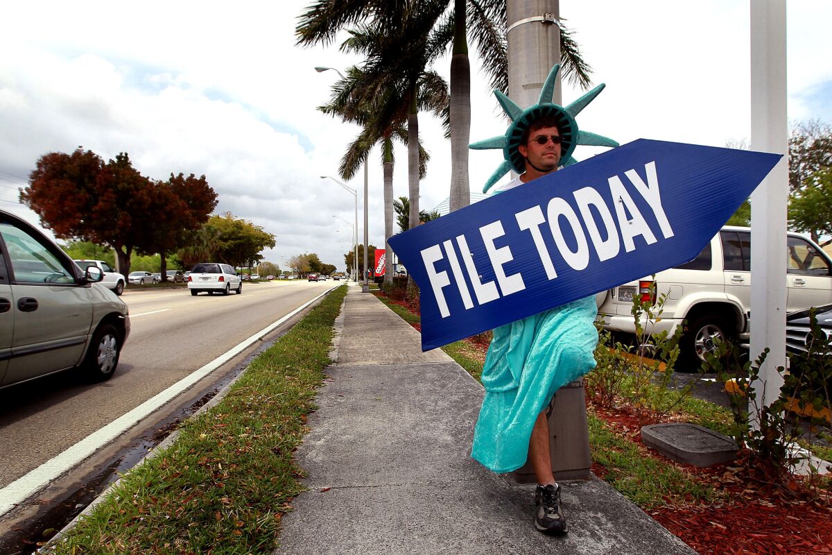 Craig Baldwin, dressed as the Statue of Liberty, holds a sign advertising a tax preparation office in Miami in 2010.