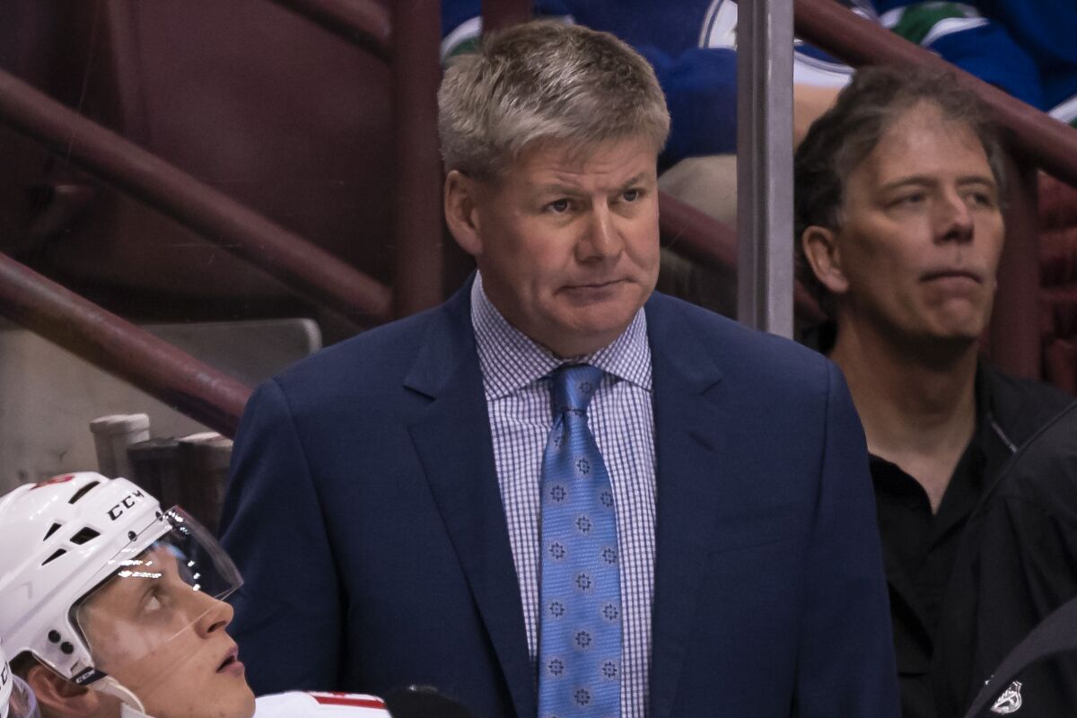 Calgary Flames coach Bill Peters stands behind the bench.