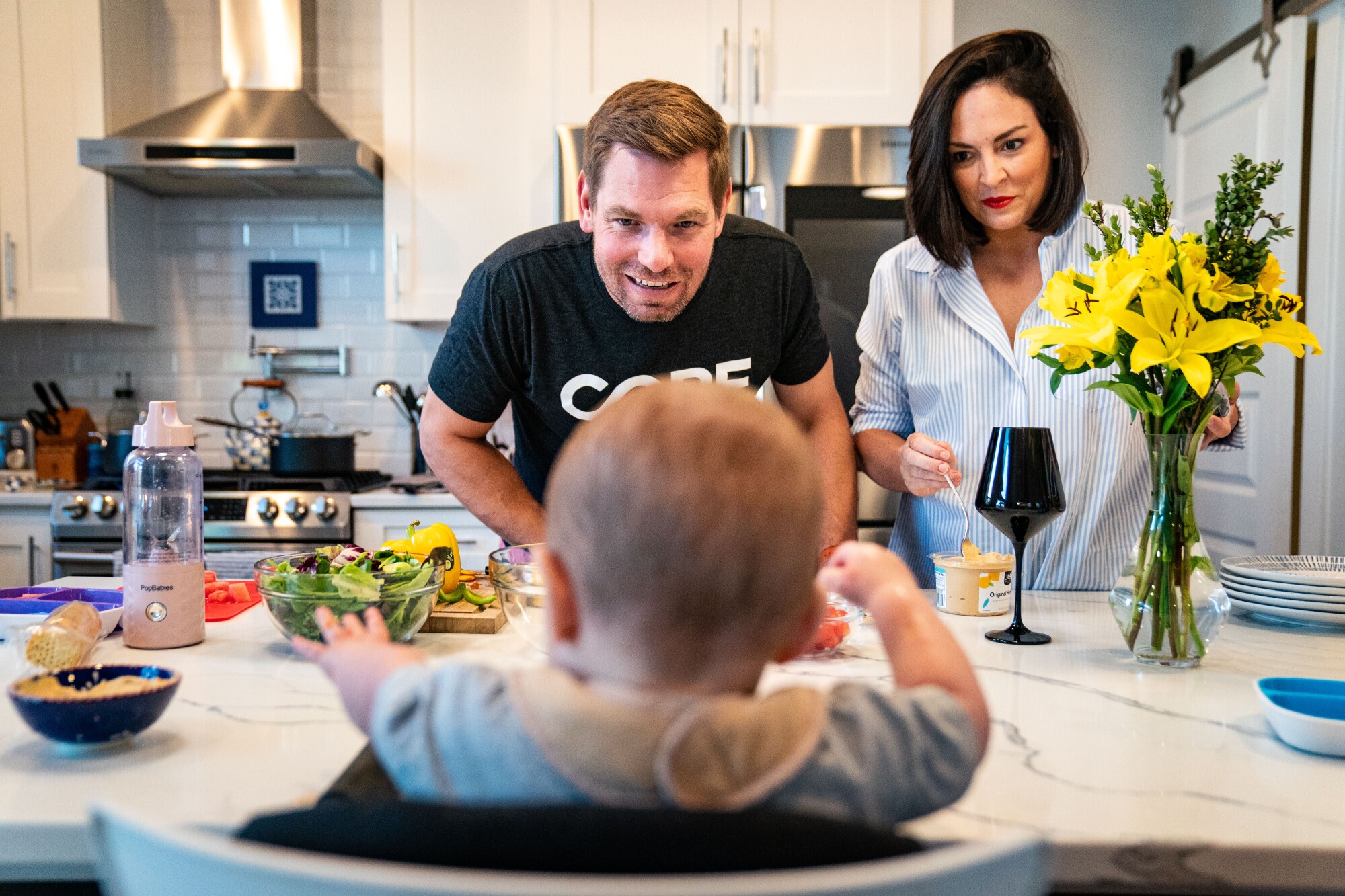 Eric Swalwell and his wife smile at their baby in his high chair.