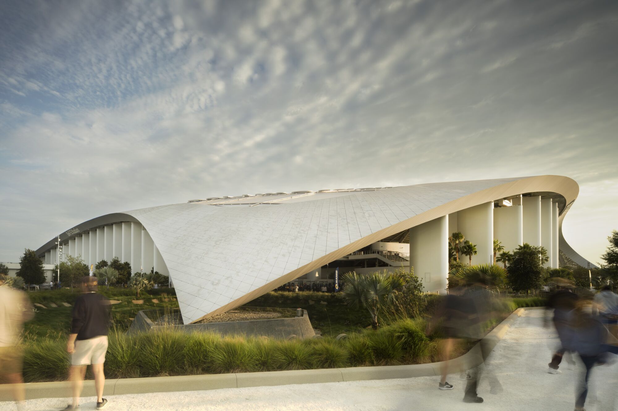 A side view of SoFi shows the curving roof touching down into a point amid landscape.