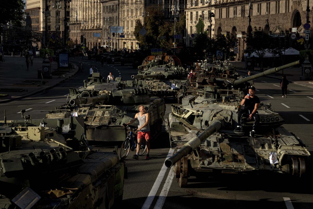 People walk among destroyed Russian military vehicles installed in downtown Kyiv.