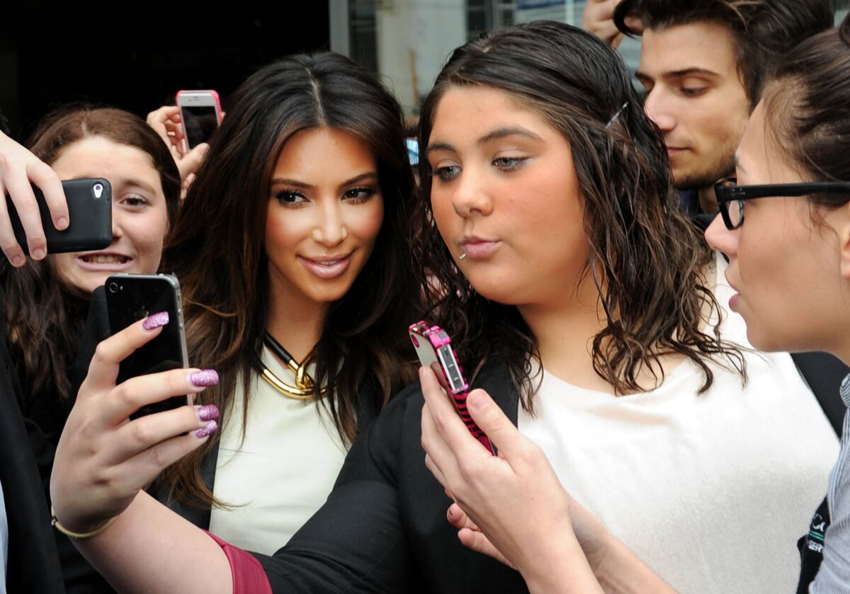 In this photo from Sept. 21, 2012, Kim Kardashian is surrounded by fans attempting to take photos of themselves with her as she leaves a radio station in Melbourne, Australia. England's Oxford University press declared "selfie" the word of the year for 2013 on Tuesday.