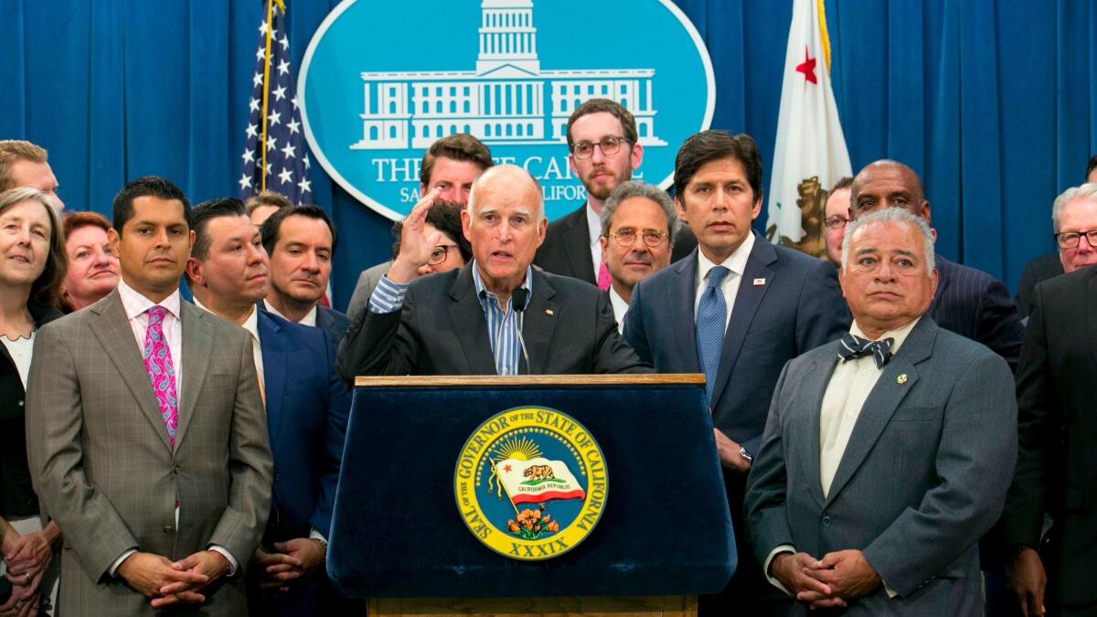 Gov. Jerry Brown is flanked by lawmakers from both sides of the aisle while speaking about the renewal of California's cap-and-trade program on July 17.