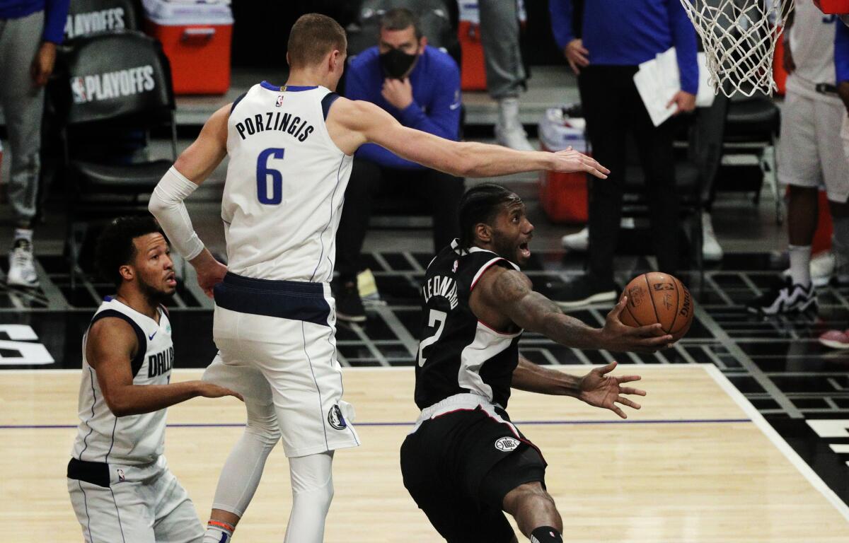 Clippers forward Kawhi Leonard is fouled by Dallas Mavericks center Kristaps Porzingis as he scores a basket.