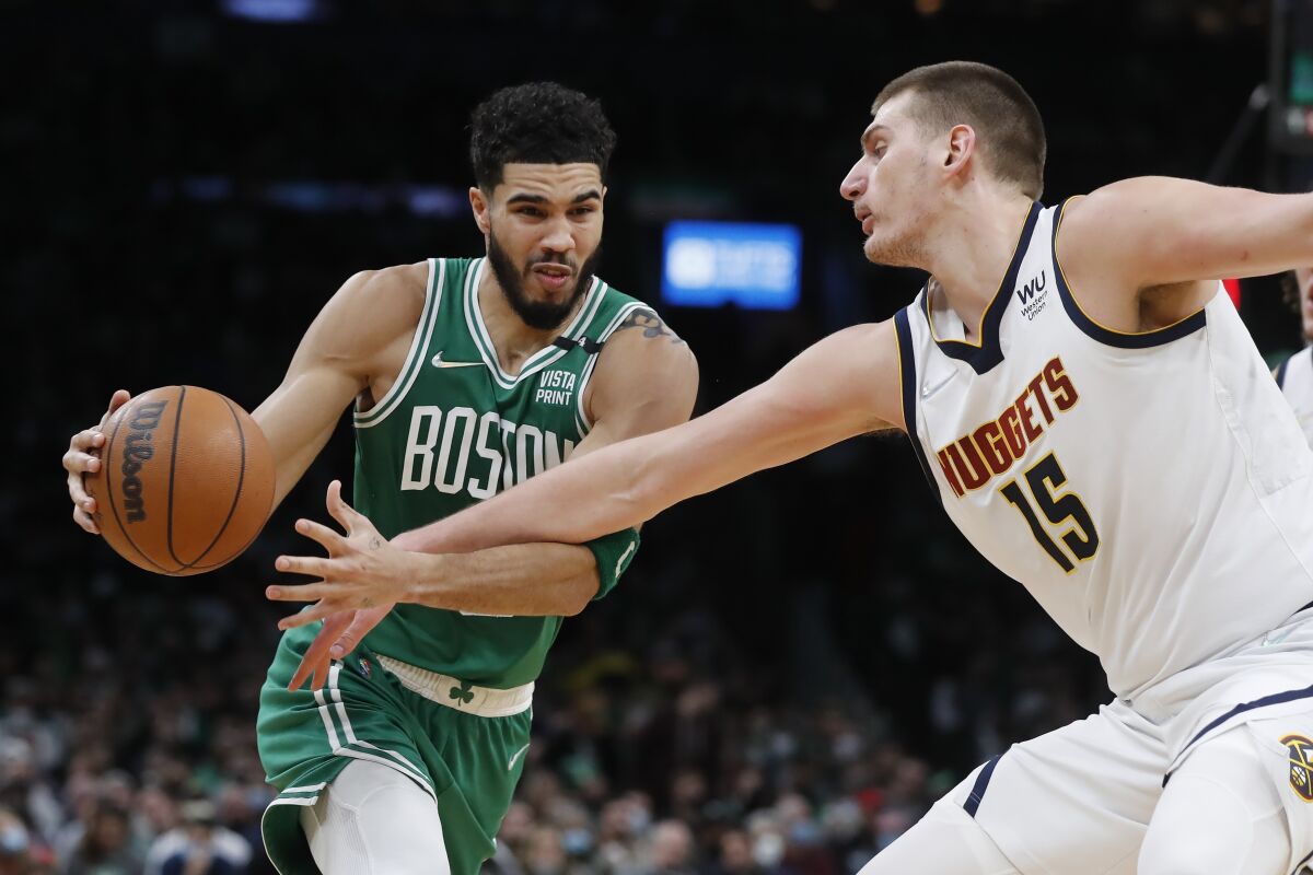 Boston Celtics' Jayson Tatum (0) drives against Denver Nuggets' Nikola Jokic (15) during the first half of an NBA basketball game Friday, Feb. 11, 2022, in Boston. (AP Photo/Michael Dwyer)