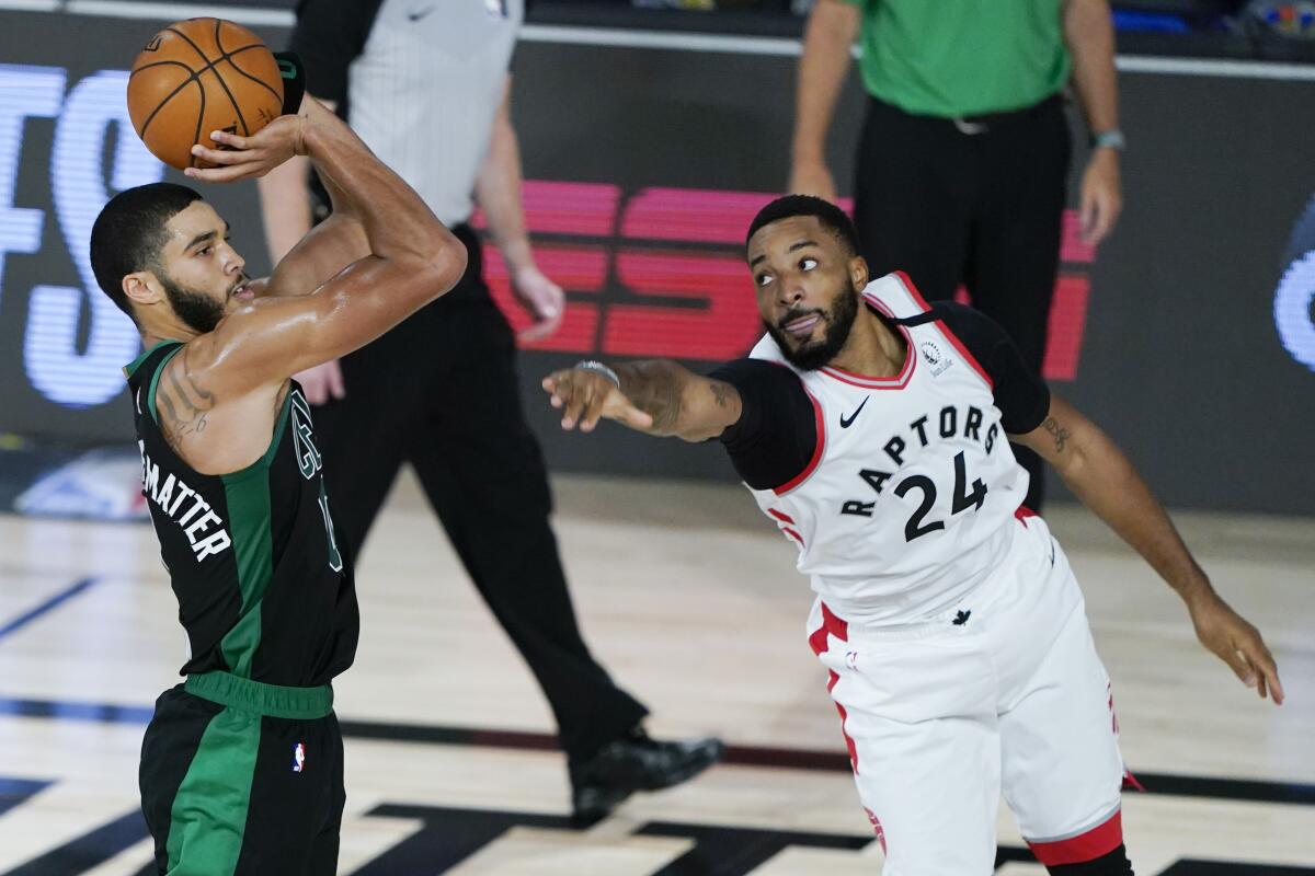 Jayson Tatum de los Celtics de Boston lanza mientras Norman Powell de los Raptors de Toronto defiende