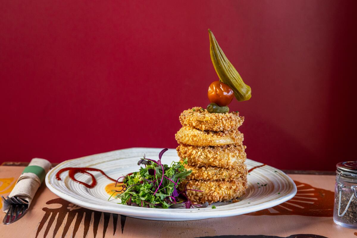 A stack of fried green tomatoes with a side salad and remoulade.