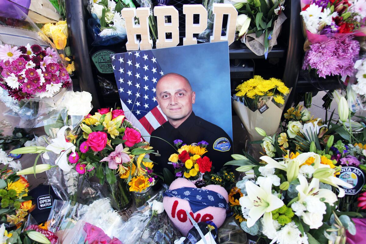 Flowers surround a photograph of Huntington Beach Police Officer Nicholas Vella outside of the HBPD headquarters on Monday.