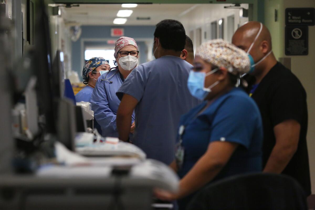 Healthcare workers in scrubs and masks in a hospital hallway