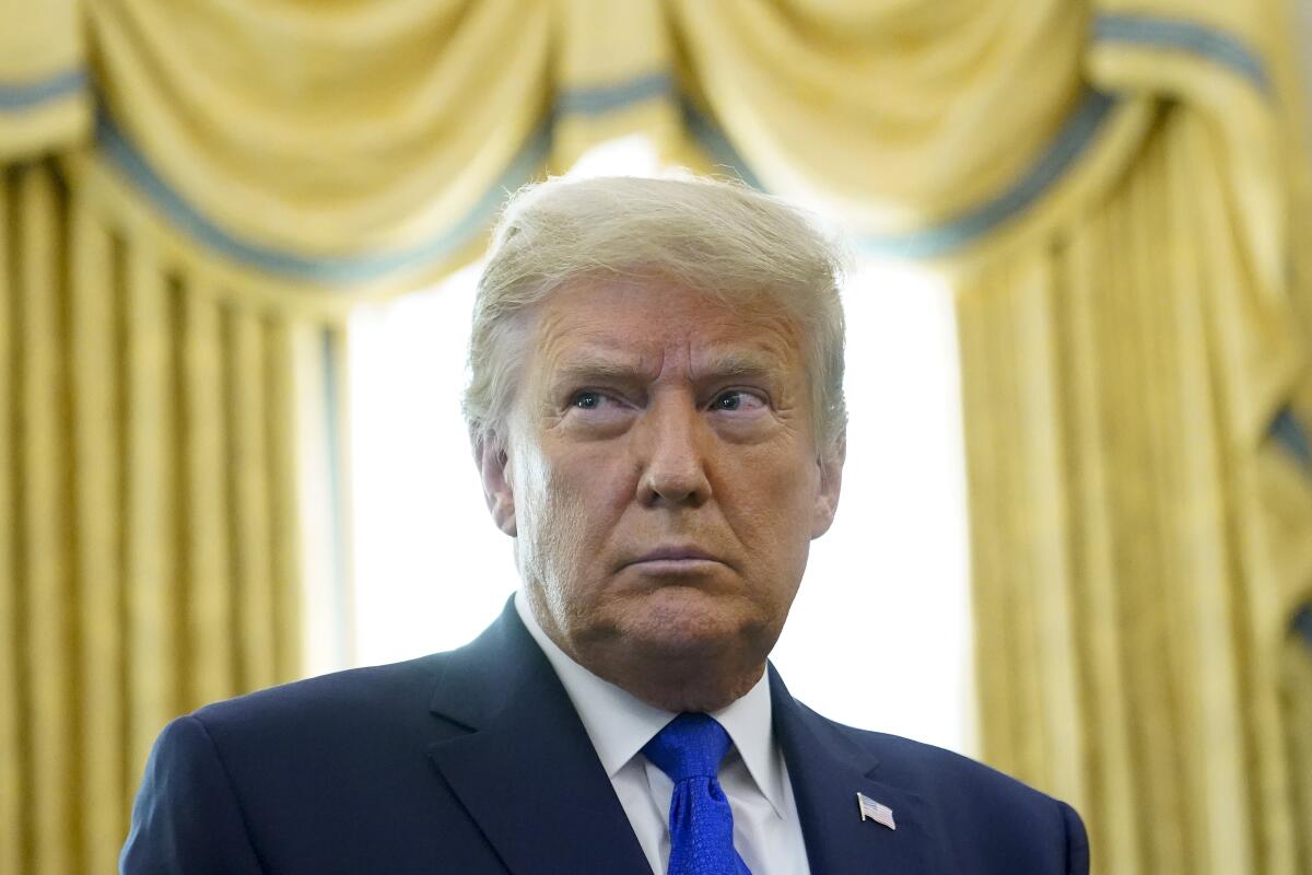 President Trump stands in the Oval Office. 