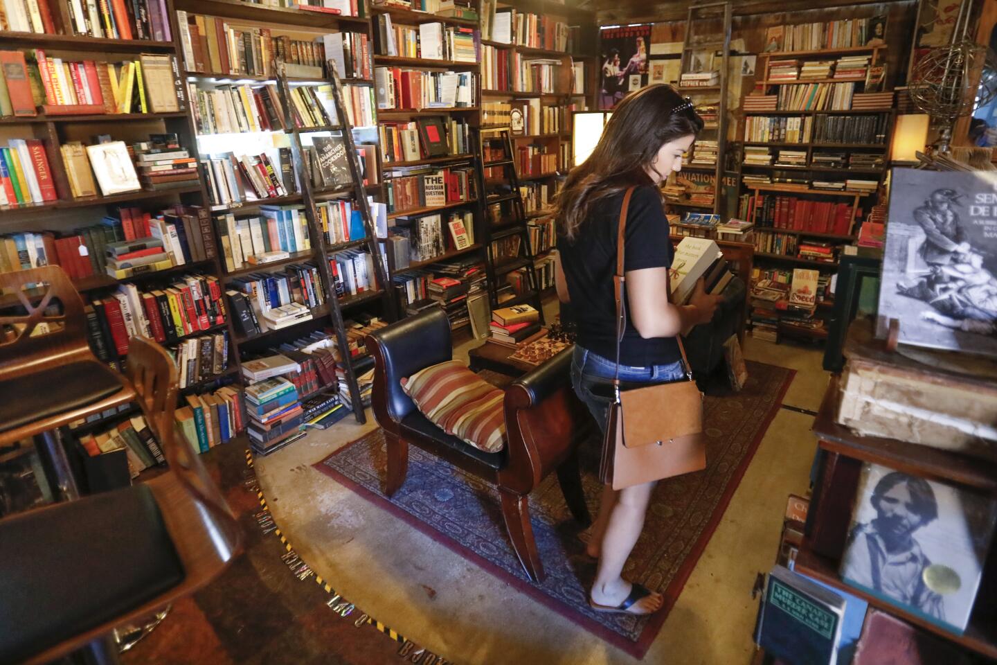 Rebecca Reiser of Carlsbad browses the books at Lhooq Books, a funky vintage bookstore in Carlsbad Village. Sean Christopher, the owner recently received a 60-day eviction notice for both the shop and the adjoining house where he has raised his son, alone. He's hoping to achieve a stay of eviction on the property long enough to sell off his book inventory and find a new space without going bankrupt and ending up homeless with his son.