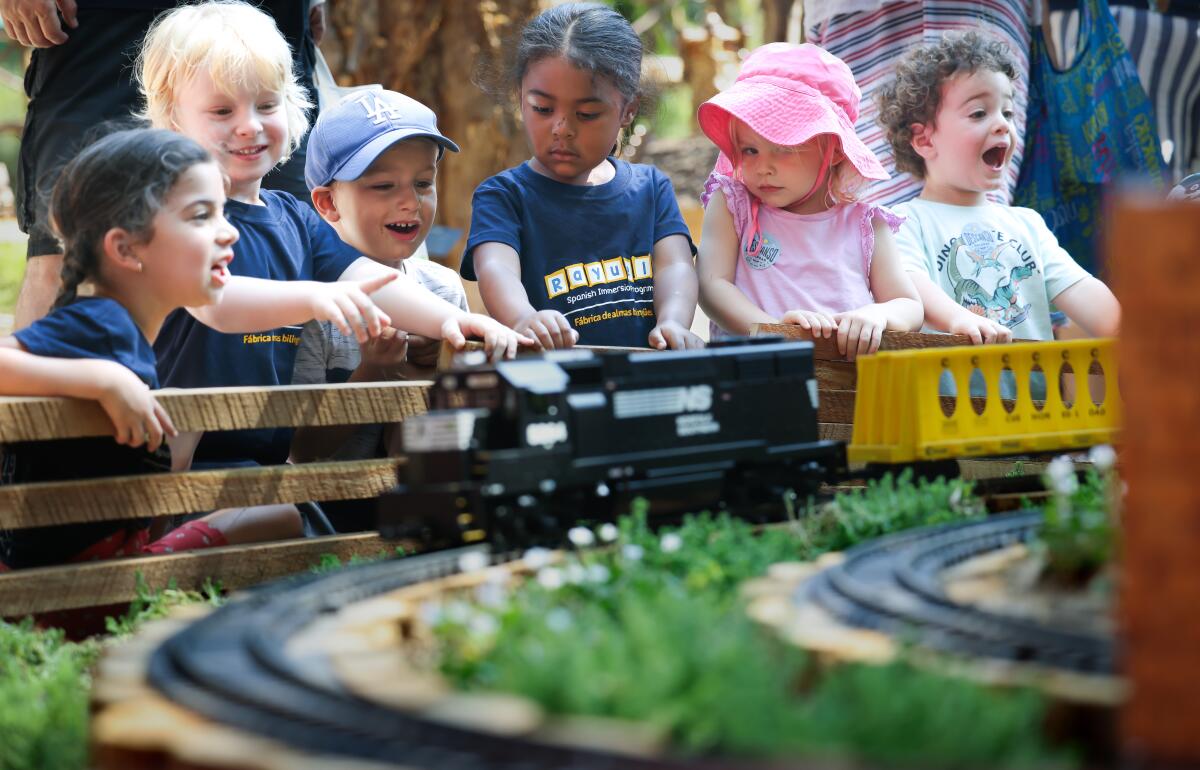 A group of young children watch miniature trains go by.