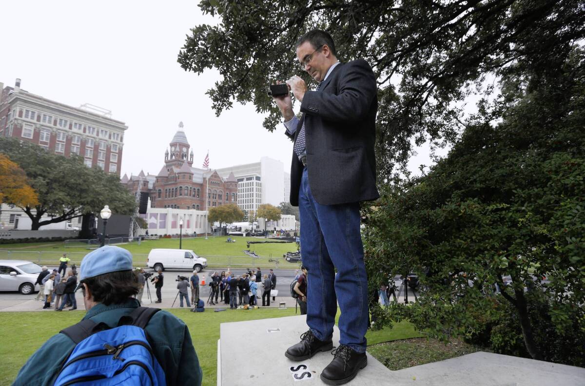 Gilbert Guindon of Quebec City, Canada, uses his camera at the spot overlooking Dealey Plaza in Dallas where Abraham Zapruder filmed President Kennedy’s assassination 50 years earlier.