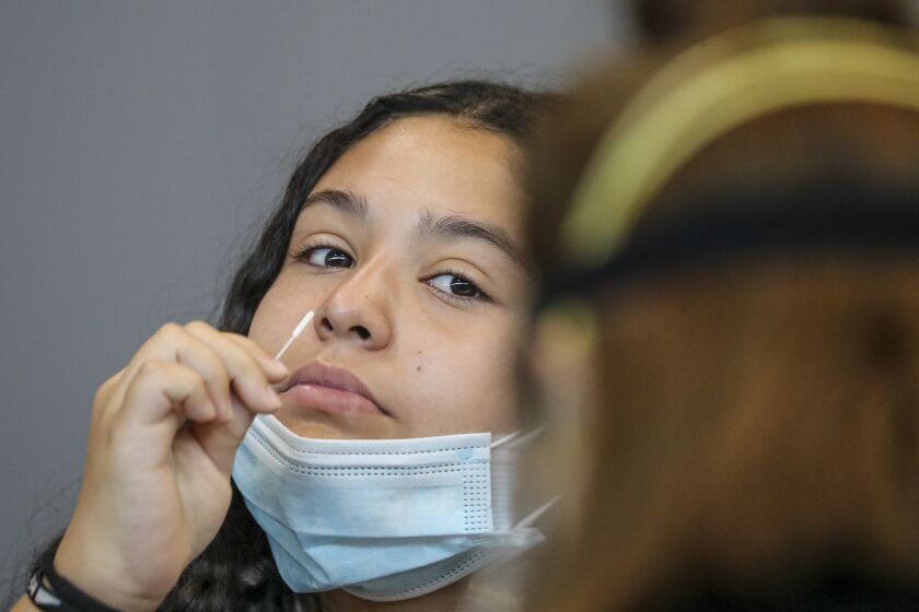 RANCHO CUCAMONGA, CA - AUGUST 20: Julissa Aguirre, 12, collects nasal specimen by self swabbing at Community COVID-19 testing site held by San Bernardino County Department of Public Health at Rancho Sports Center on Thursday, Aug. 20, 2020 in Rancho Cucamonga, CA. (Irfan Khan / Los Angeles Times)