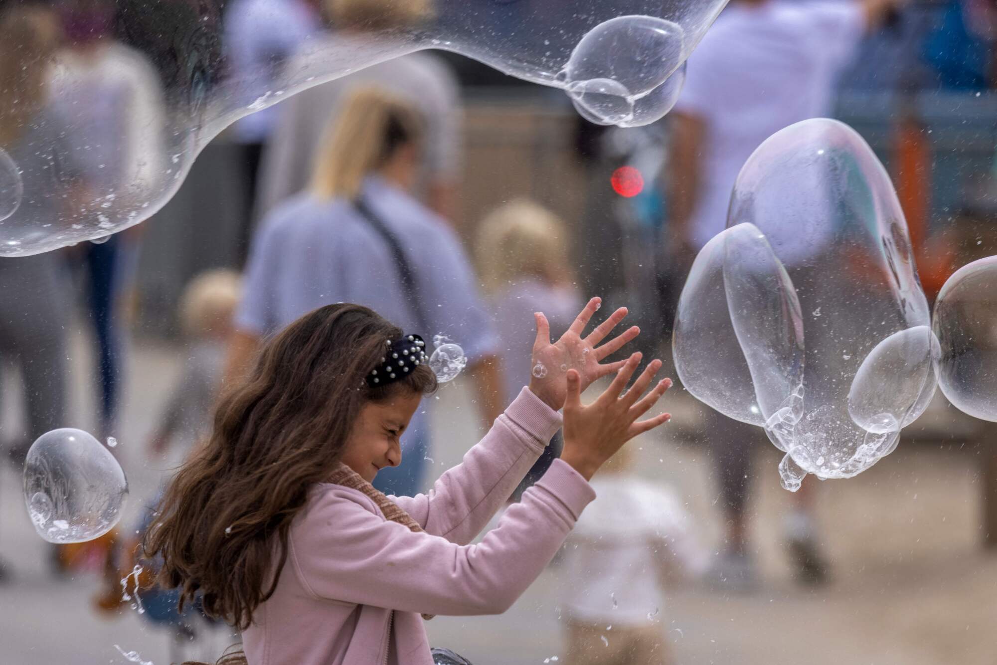 A girl reaches for bubbles near the Santa Monica Pier.