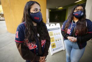 LOS ANGELES, CA - APRIL 27: James A. Garfield High School senior leadership team students Sarahi Bahena, left, and Edith Ramirez, wait to greet incoming Freshmen students as they arrive for their first time on campus. Some Freshman LAUSD students and staff are welcome at Garfield High School for the first time in more than a year. James A. Garfield High School on Tuesday, April 27, 2021 in Los Angeles, CA. (Al Seib / Los Angeles Times).