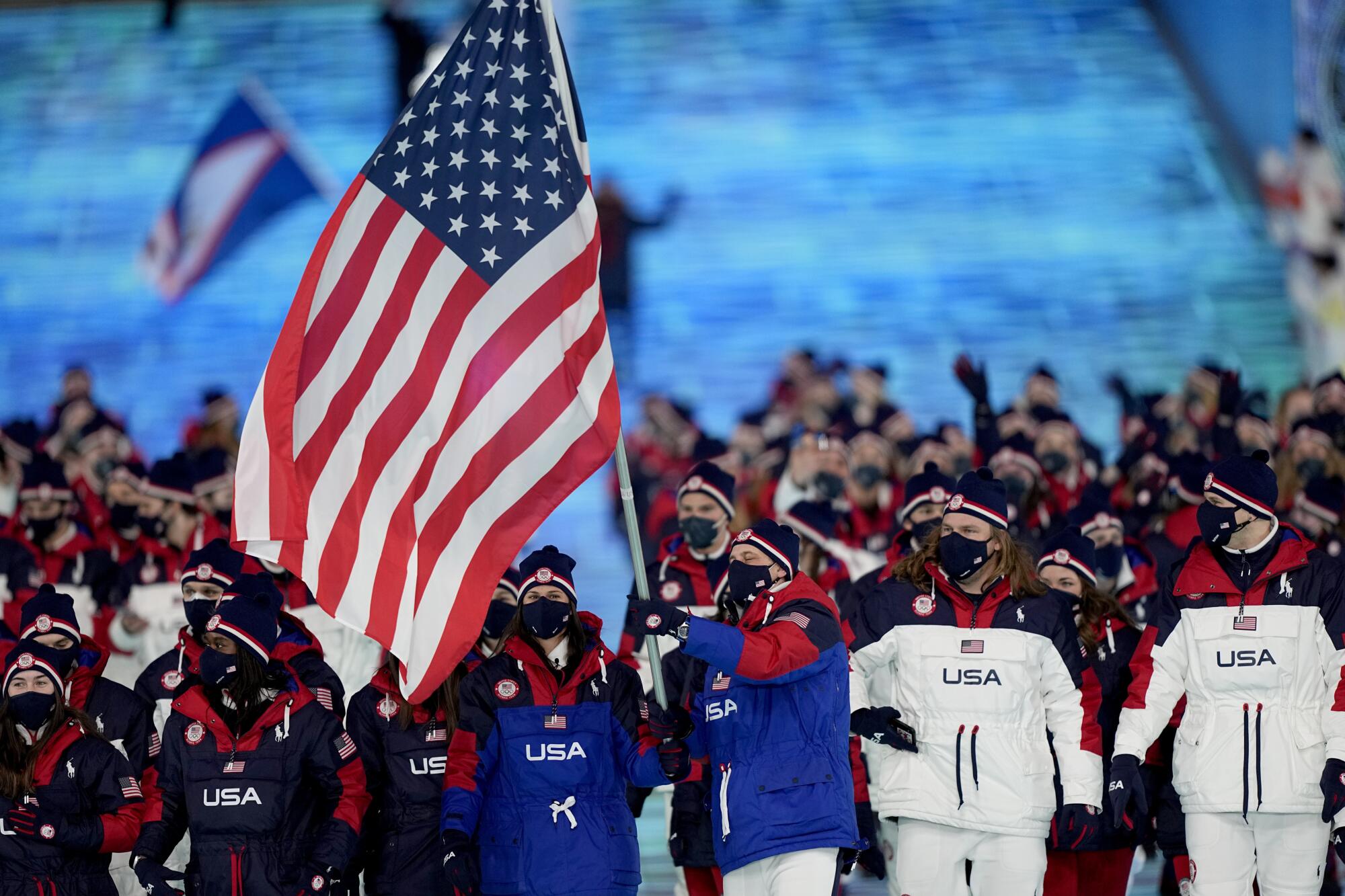 Brittany Bowe and John Shuster lead their team in during the opening ceremony of the 2022 Winter Olympics