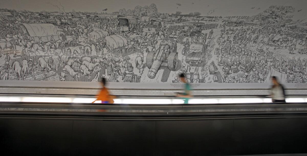A moving walkway in the Montparnasse Metro station in Paris carries commuters past Joe Sacco's massive cartoon mural depicting the first day of the 1916 Battle of the Somme.