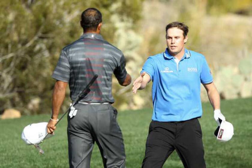 Tiger Woods, left, shakes hands with Nick Watney on the 18th hole after Watney defeated him in the second round of the World Match Play Championship.