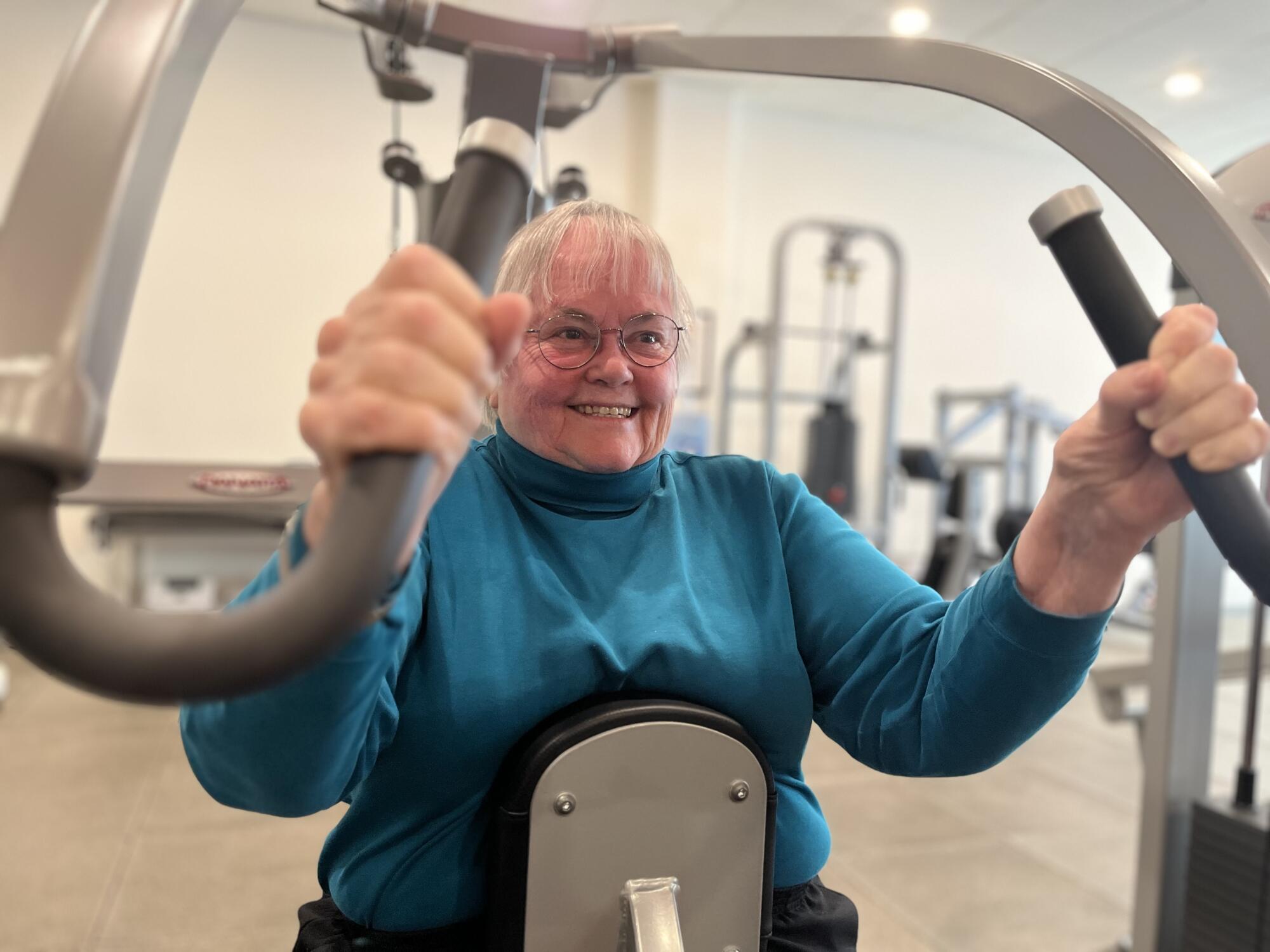 An 80-year-old woman lifts weights at the gym.