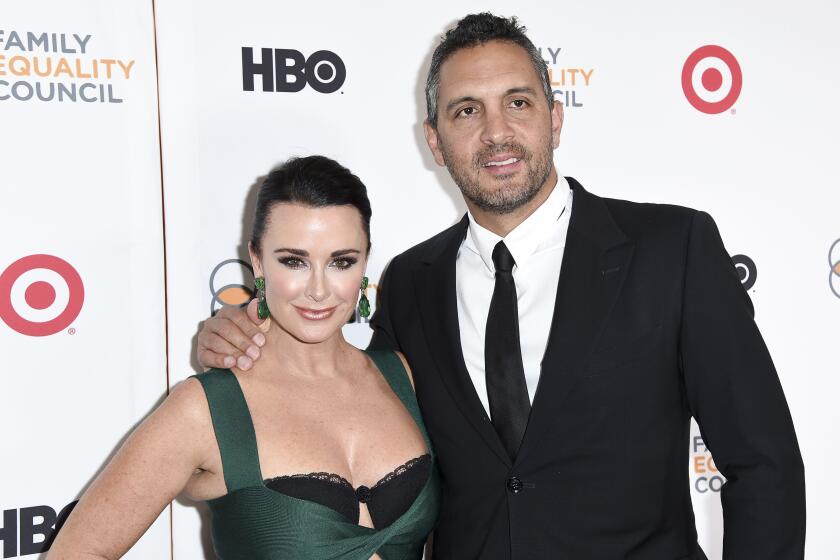 Kyle Richards and Mauricio Umansky pose together in formal attire against a white backdrop.