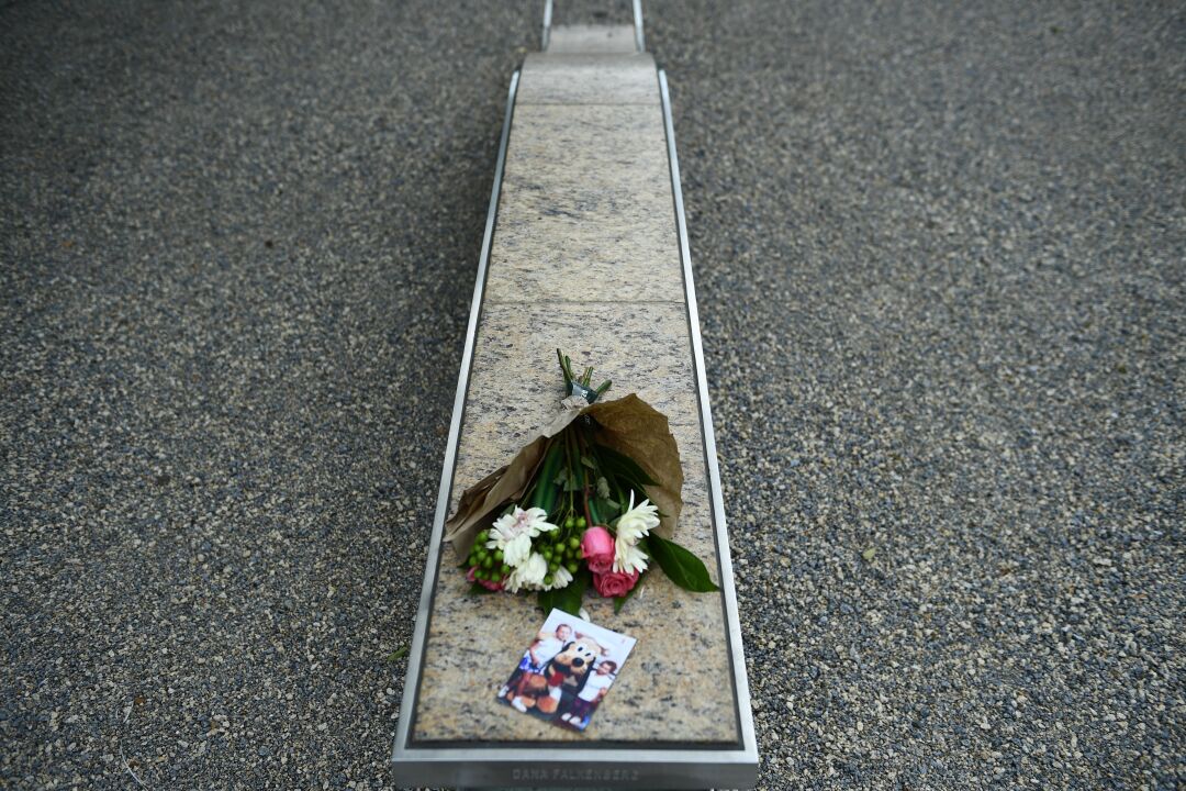 Flowers are left next to a picture on a bench.