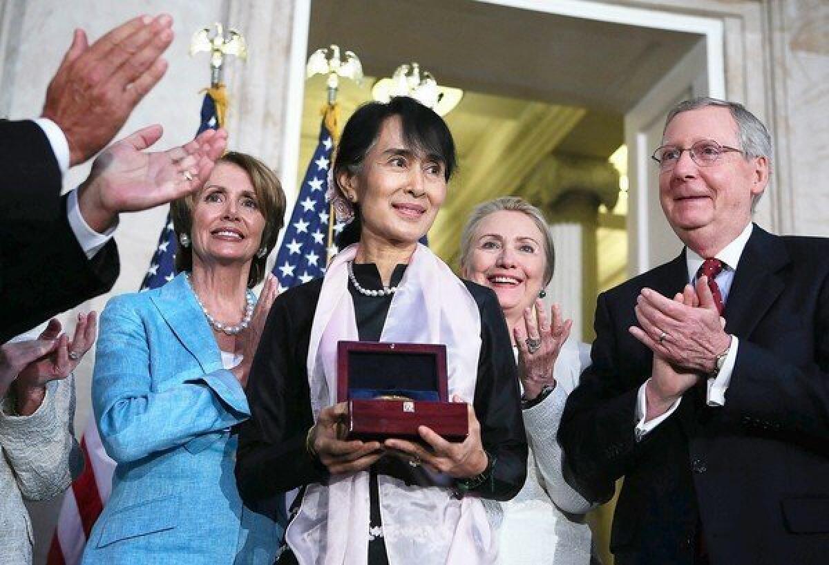 Myanmar opposition politician Aung San Suu Kyi holds her Congressional Gold Medal as House Minority Leader Nancy Pelosi (D-San Francisco), left, U.S. Secretary of State Hillary Rodham Clinton and Senate Minority Leader Mitch McConnell (R-Ky.) applaud at the U.S. Capitol.