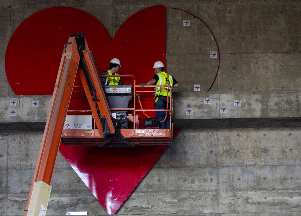 Construction workers install a giant heart at one end of the 3rd Street Tunnel.