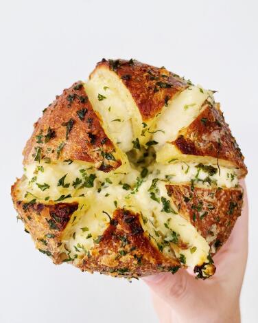 A hand holds up a garlic-butter bagel from Calic Butter from Korean-inspired pop-up Calic Bagels in Westlake L.A.