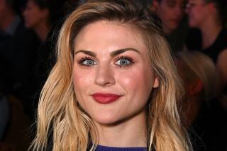 Frances Bean Cobain is smiling  and wearing a black jacket and blue t shirt 