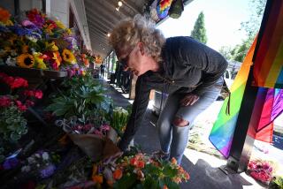 A resident leaves flowers at a makeshift memorial outside the Mag.Pi clothing store in Cedar Glen, near Lake Arrowhead, California, on August 21, 2023. The owner of the store, Laura Ann Carleton, was fatally shot on August 18 by a man who "made several disparaging remarks about a rainbow flag" displayed outside her store, according to the San Bernardino County Sheriff's department. The suspect was later killed during an encounter with deputies. (Photo by Robyn Beck / AFP) (Photo by ROBYN BECK/AFP via Getty Images)
