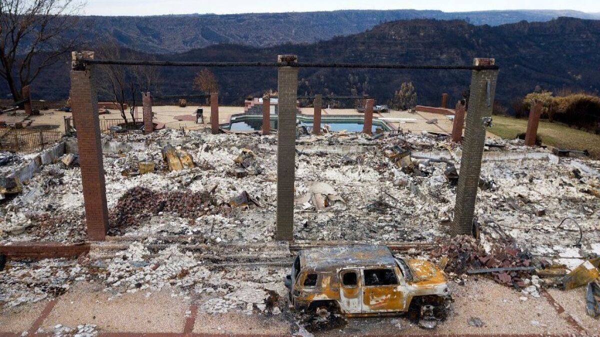 A burned vehicle sits in front of a home leveled by the Camp fire in Paradise, Calif.