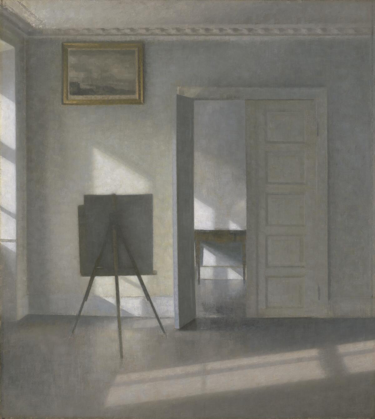 A painting in muted tones shows beams of light penetrating a room with a canvas on an easel and on a wall.