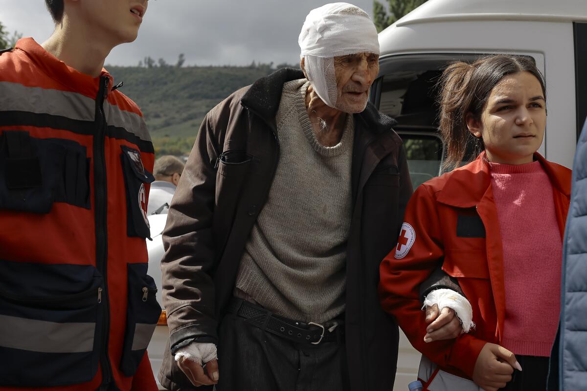 Wounded man with bandaged head being helped by volunteers