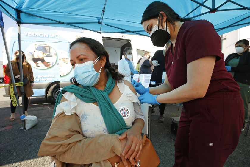 VERNON, CA - MARCH 17: Cristina Vasquez gets the Pfizer vaccine shot from Physician Assistant-Certified Alyssa Hernandez as the city of Vernon Health Department staff used the city's new mobile health unit clinic to administer COVID-19 vaccinations to nearly 250 essential food processing workers at Rose & Shore, Inc., a major, locally-based prepared foods products producer that serves supermarkets, schools, restaurants, airlines and others. The vaccinations were administered onsite, at the company's 70,000 square foot facility in Vernon. The City of Vernon has partnered with Stacy Medical Center to vaccinate 11,000 Vernon- based workers performing essential jobs in high-density work environments such as large-scale food processing, cold storage and food warehousing facilities. Vernon City Administrator Carlos R. Fandino, Jr. said, "The City of Vernon has taken a pro-active stance to protect the community from COVID-19. Vernon's Health Department has mobilized to deliver life-saving COVID vaccines to essential workers who put their lives on the line producing food and everyday items. Vernon's businesses are pleased that the city now has the mobile health clinic to help protect their essential employees against the potentially deadly coronavirus and mitigate the virus's spread at their processing plants. Administering COVID-19 vaccines to their workers while they're on- the-job ensures accessibility for a population that is largely underserved and the hardest hit by the pandemic." "Our mobile delivery method is extremely efficient. Vernon's Health Department has inoculated over 3,000 essential workers in its initial thirteen days of operation, with another 1,000 expected this week as the mobile vaccine unit visits additional plants daily. We are vaccinating as quickly as state and county public health officials provide us with vaccines." Mr. Fandino said. Rose & Shore, Inc on Wednesday, March 17, 2021 in Vernon, CA. (Al Seib / Los Angeles Times).