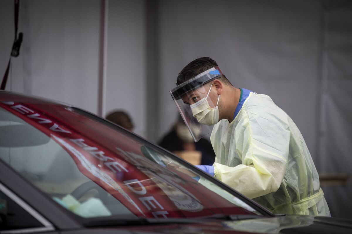 Healthcare workers speak with drivers at a drive-through coronavirus testing site at the Rose Bowl in Pasadena.