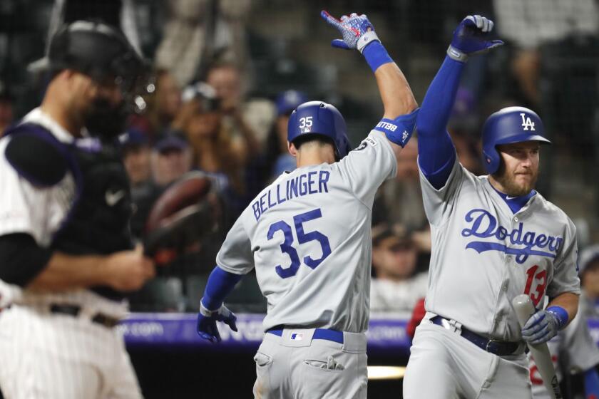 Los Angeles Dodgers' Cody Bellinger, center, celebrates hitting a solo home run with Max Muncy, right, as Colorado Rockies catcher Chris Iannetta stands in the foreground in the eighth inning of a baseball game Sunday, April 7, 2019, in Denver. (AP Photo/David Zalubowski)