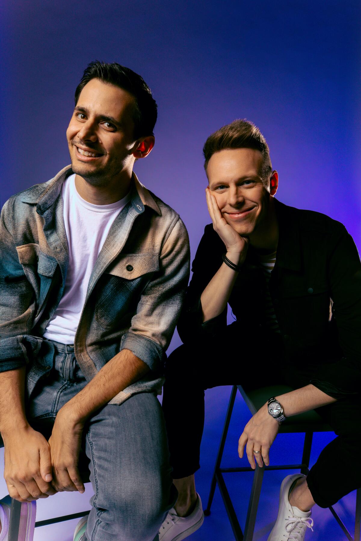 Benj Pasek and Justin Paul sit together casually for a portrait.