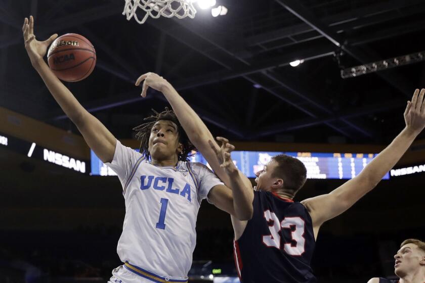 UCLA center Moses Brown, left, loses his grip on the ball as he is defended by Belmont center Nick Muszynski during the second half of an NCAA college basketball game Saturday, Dec. 15, 2018, in Los Angeles. (AP Photo/Marcio Jose Sanchez)