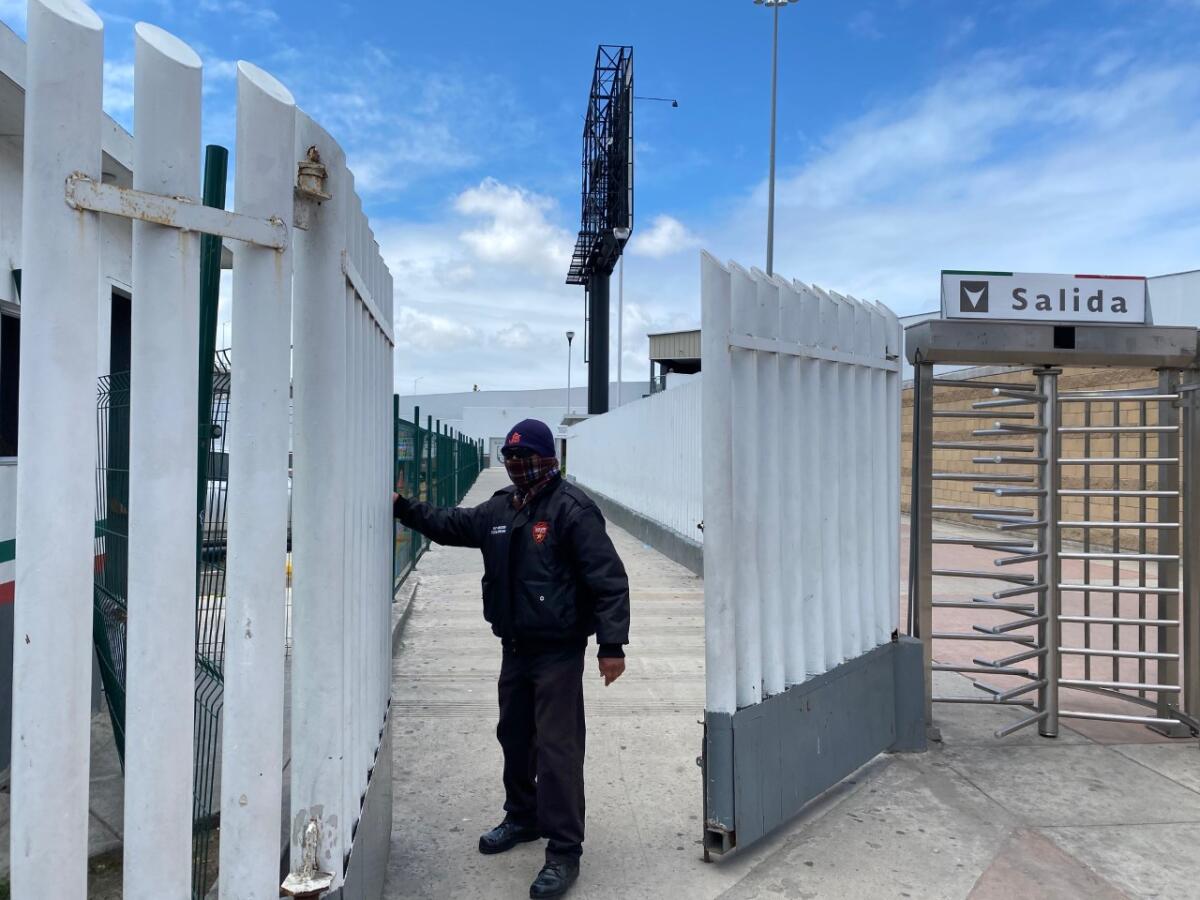Tijuana security guard Fernando Reyes closes the gate accessing the Pedestrian West footbridge Monday. The border crossing was temporarily shuttered Sunday in response to decreases in traffic since the coronavirus-related restrictions to non-essential travel took place.