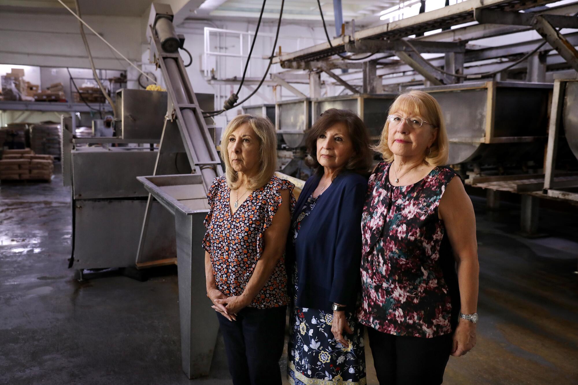 Three women stand next to one another in a factory