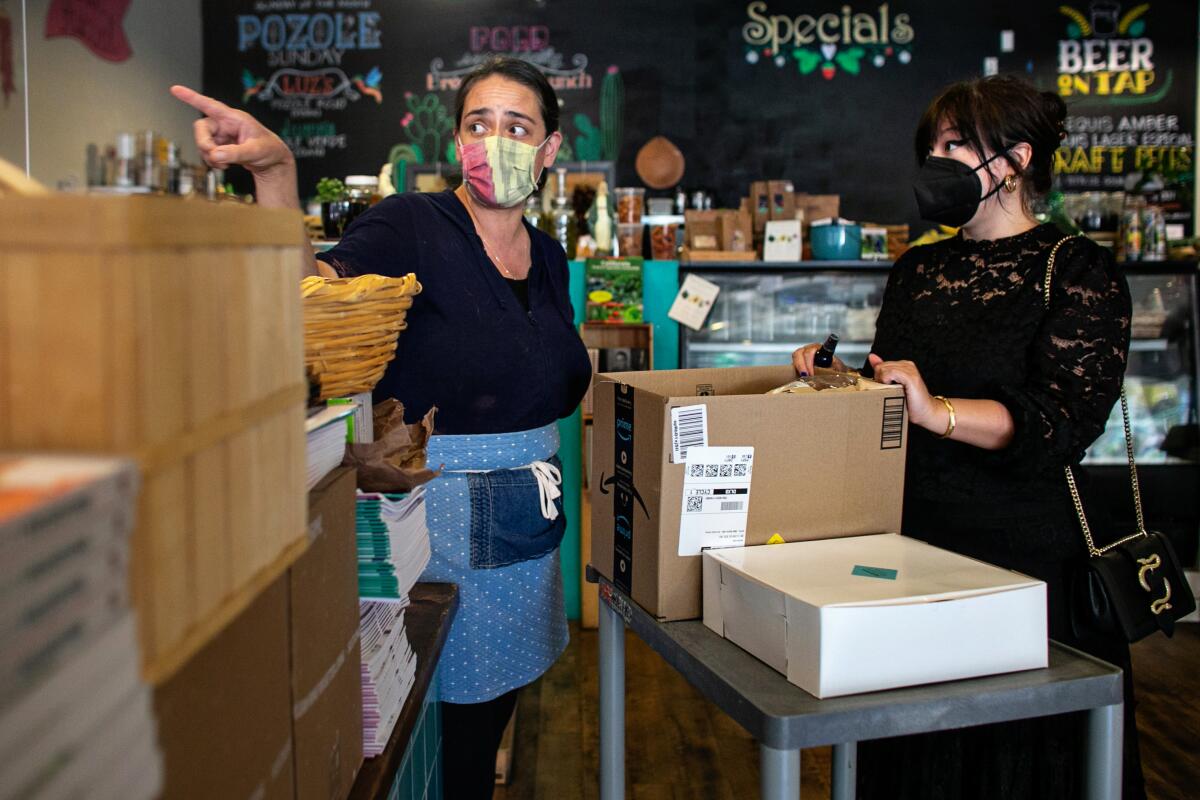 A woman points to assist a masked customer at her store.