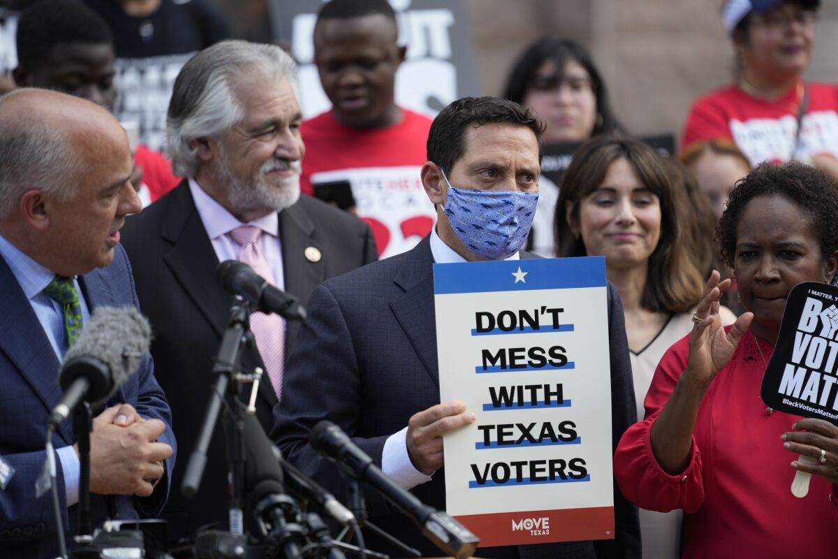 Trey Martinez Fischer, in a mask, holds a sign that reads "Don't mess with Texas voters."