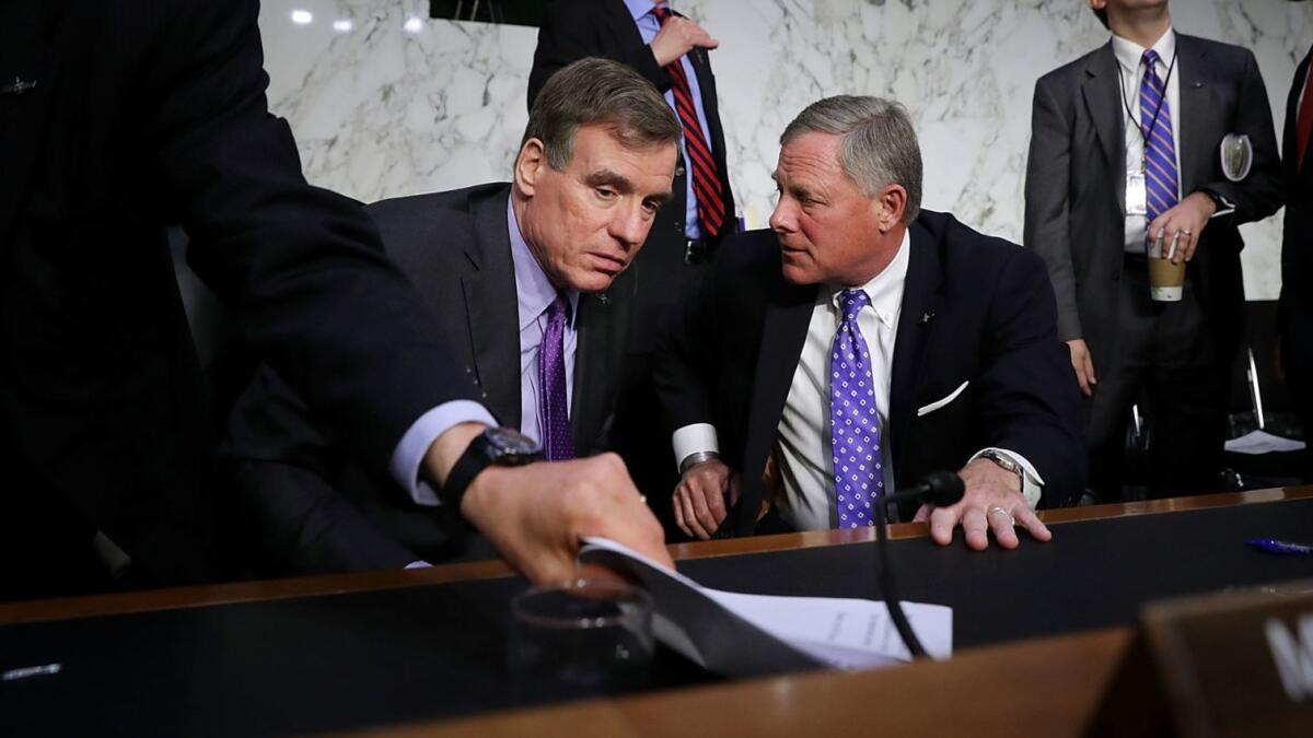 Sens. Mark R. Warner (D-Va.), left, and Richard M. Burr (R-N.C.), the leaders of the Senate Intelligence Committee, confer after the hearing.