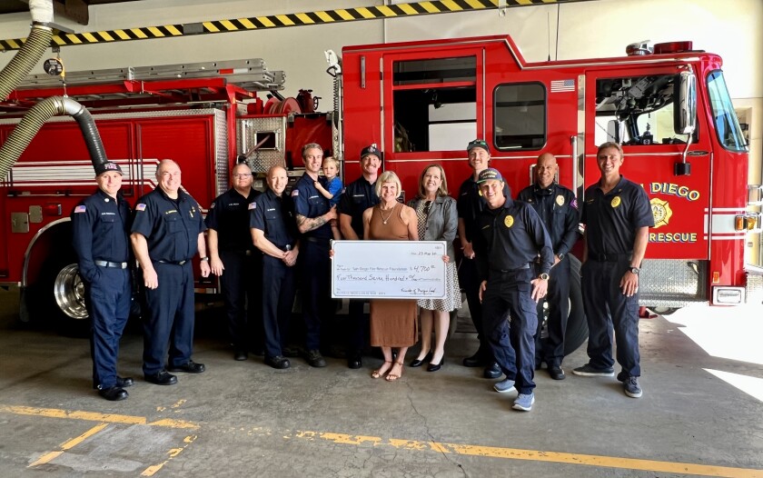 Margie Lord of La Jolla holds a check for $4,700 for the San Diego Fire Rescue Foundation. 