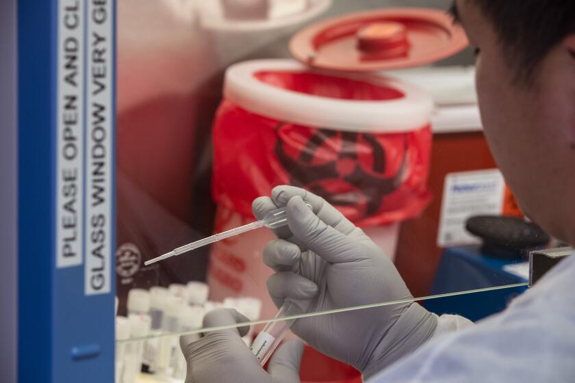 BRENTWOOD, CALIF. -- SATURDAY, MARCH 28, 2020: A medical technologist moves samples in a biological safety cabinet at the UCLA clinical microbiology lab in Brentwood, Calif., on March 28, 2020. (Brian van der Brug / Los Angeles Times)