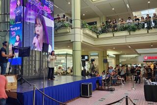 A woman performs at a karaoke competition in a mall